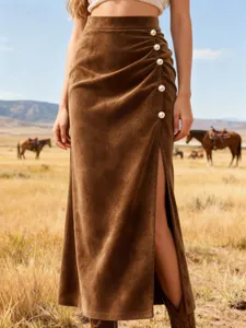 Detail of a brown suede midi skirt with high waist, pearl buttons, and a side slit.