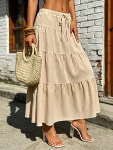 Detail view of a boho beige tiered maxi skirt featuring pleated texture and drawstring waist