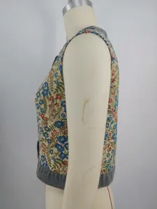 Side view of a vintage floral jacquard sleeveless vest with denim trim accents.