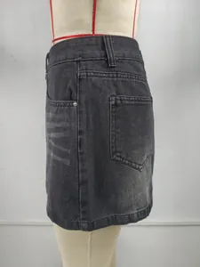 Gros plan d'une mini-jupe en jean noir délavé avec effet moustaches et détails cloutés.