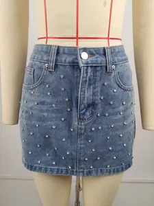 Détail de la mini-jupe en jean délavé ornée de strass brillants pour un look moderne.