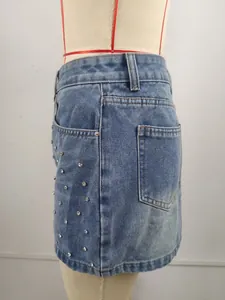 Détail latéral d'une mini-jupe en jean délavé avec des ornements en strass dispersés.
