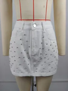Détail d'une mini-jupe en jean blanc avec des strass brillants sur un mannequin de couture