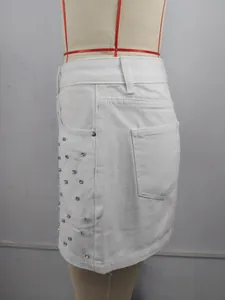 Détail rapproché montrant les clous en strass argentés sur la jupe en jean blanc
