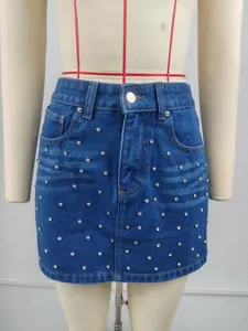 Détail d'une mini-jupe en jean bleu avec fini délavé et ornements en strass brillants