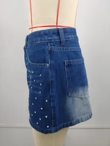 Gros plan d'une mini-jupe en jean délavé bleu avec des strass étincelants et une poche