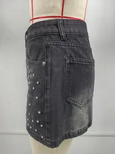 Détails de mini-jupe en jean noir délavé ornée de strass brillants étincelants.