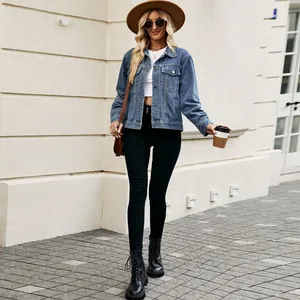 Trendy women's washed blue short denim jacket styled in a chic casual outdoor setting