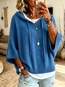 Oversized blue hooded knit sweater with drawstrings shown in a casual lifestyle setting