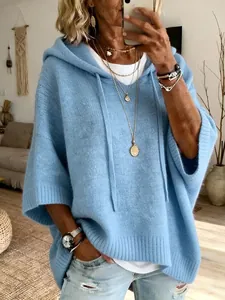 Close-up of a casual light blue knit hooded poncho sweater with drawstring detail.