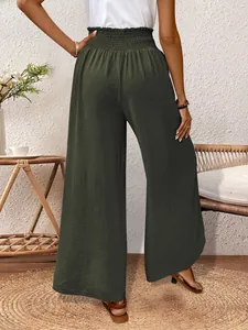 Back view of elegant dark green wide-leg trousers with side slit and smocked waist