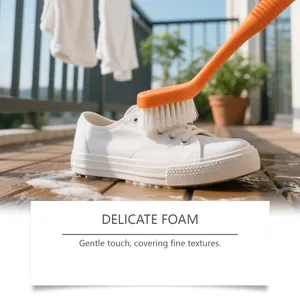 Long-handled orange brush cleaning a white sneaker with delicate foam on a balcony.