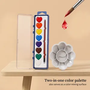 Close-up of heart-shaped watercolor paint set with brush and mixing palette