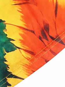 Close-up of vibrant bohemian leaf print and fine yellow stitching on halter dress