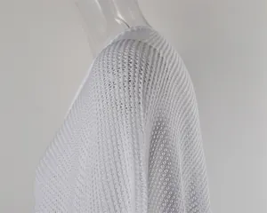 Detailed view of the intricate white hollow-out knit mesh fabric on a beach cover-up