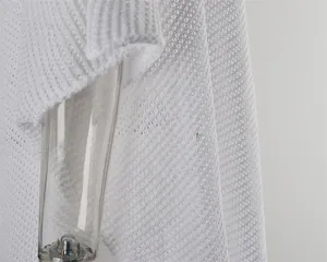 Close-up detail of the premium white hollow-out crochet knit fabric on a beach cover-up