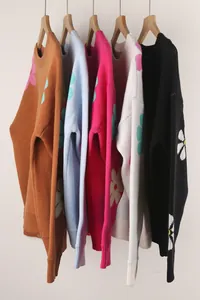 Detail view of colorful floral pattern knitted sweaters hanging on wooden hangers