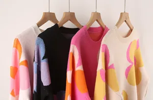 Detailed view of colorful women's knitted sweaters with large floral patterns on hangers