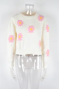 Close-up of a white knit sweater featuring pink daisy patterns and a round neck