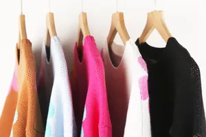 Close-up of vibrant flower pattern color-block crewneck knit sweaters on hangers