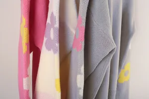 Macro detail showing soft knit fabric and colorful floral sleeve pattern on a sweater