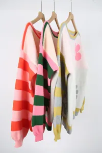 Side view of colorful striped and floral oversized knitted sweaters on wooden hangers.