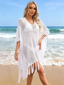 Detailed view of white hollow knit beach cover-up featuring tassel hem and loose silhouette