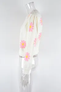 Side view detail of fashionable white knit sweater with pink and yellow daisy floral patterns