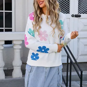 Close-up of white knit sweater featuring colorful floral patterns and round neck