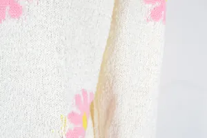 Detail shot of soft knit fabric texture on cream daisy floral pattern sweater