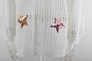 Dettaglio ravvicinato di un copricostume bianco traforato con toppe a stella di paillettes
