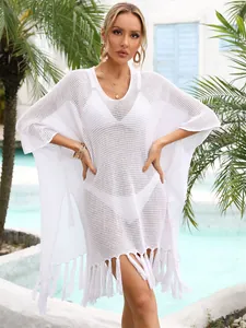 Close-up of white crochet beach cover-up with tassels and hollow knit detail.