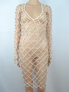 Detail des weißen Häkel-Strandkleids mit Mesh-Struktur und goldenen Perlenverzierungen