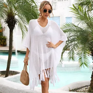 White crochet tassel beach cover-up shown on a model in a tropical resort setting