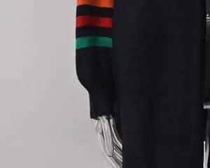 Gros plan d'un pull en maille noir avec des manches à rayures colorées vibrantes