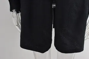 Détail de l'ourlet d'un pull en maille noire avec poignets côtelés et texture respirante.