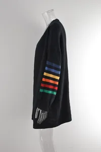 Vue latérale du pull noir oversize avec des rayures arc-en-ciel sur le détail de la manche