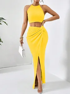 Elegant yellow pleated two-piece set featuring a halter crop top and high slit maxi skirt.