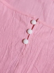 Detail of pink textured summer dress featuring three decorative white round buttons.