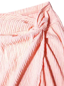 Close-up detail of a pink pleated high waist skirt featuring an elegant front knot