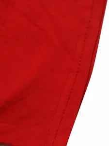 Gros plan détaillé montrant les coutures soignées et l'ourlet sur un tissu en coton rouge.