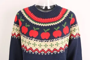 Primer plano de suéter de punto navideño azul marino con manzanas rojas y motivos.