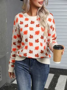 Woman wearing a cream knit sweater with orange maple leaf patterns in a street setting