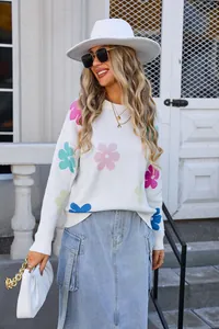 Model wearing a white crew neck sweater with colorful floral patterns and a denim skirt