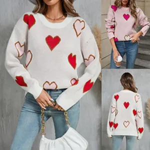 Close-up detail of women's crew neck knit sweater featuring vibrant red and pink heart patterns
