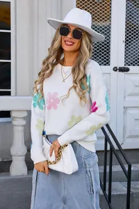 Detailed view of white knit sweater featuring colorful floral patterns and round neck