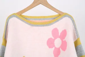 Close-up detail of a pink knitted sweater with floral pattern and striped crew neck