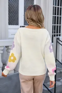 Back view of a white boat neck knit sweater with colorful floral patterns on sleeves.