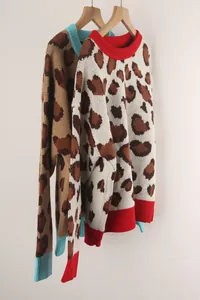 Side view of two leopard print knit sweaters with red and blue ribbed trims on hangers