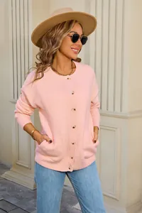 Detail of pink knitted cardigan showing soft texture, round neck and button closure